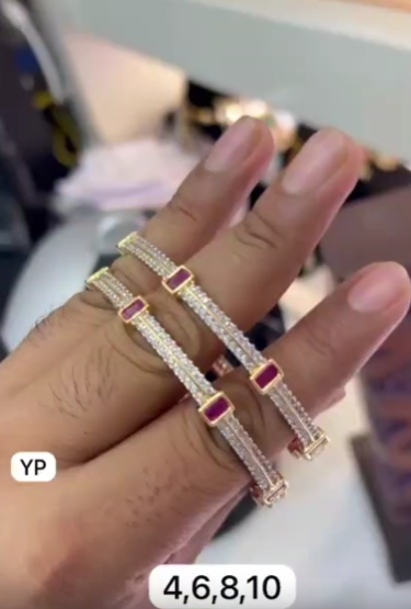 Pair of gold-plated bangles studded with white American diamonds and red square stones